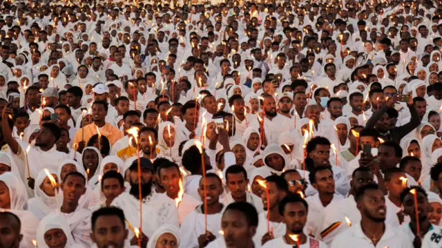 Стотине верника у белој одећи са свећама у рукама у Етиопији на божићној литургији