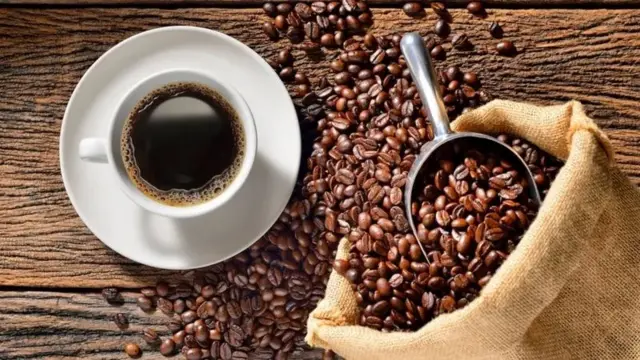 Xícara de café ao lado de grãos de café