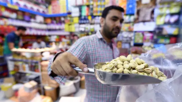 दुबई की एक दुकान में ईरान से आयातित पिस्ते बेचता एक ईरानी दुकानदार