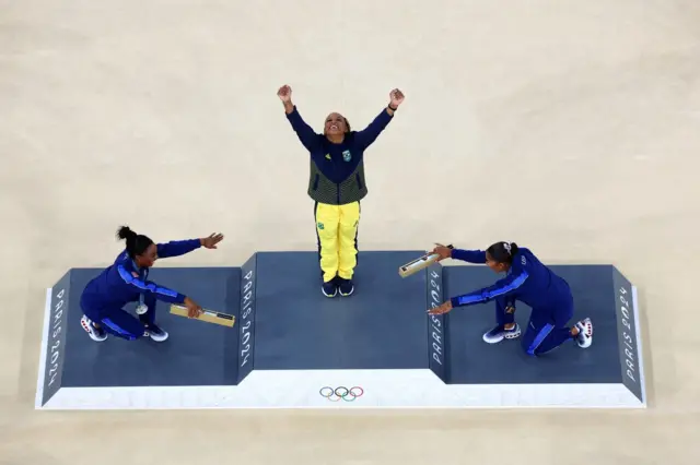 Rebeca Andrade sendo reverenciada por Simone Biles e Jordan Chiles