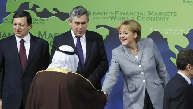 Almanya Başbakanı Angela Merkel (sağdan 2.) 15 Kasım 2008'de Washington'da düzenlenen G20 Zirvesi'nin açılışında, (soldan sağa) AB Komisyonu Başkanı Jose Manuel Barroso, İngiltere Başbakanı Gordon Brown ve Fransa Cumhurbaşkanı Nicolas Sarkozy'nin yanında aile fotoğrafı için yerlerini alırken Suudi Arabistan Kralı Abdullah ile el sıkışıyor.
