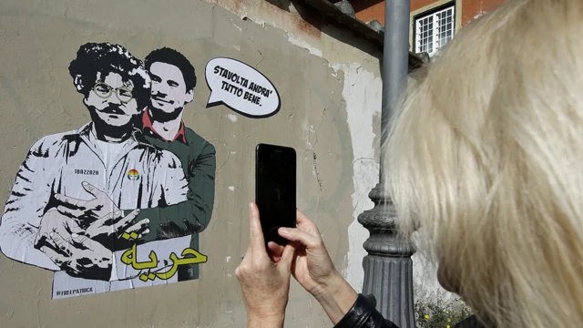 Une femme prend une photo avec un téléphone portable d'une peinture murale qui aurait été réalisée par l'artiste de rue Laika. Elle représente Patrick George Zaky (L) portant l'uniforme d'un détenu et est embrassée par Giulio Regeni (R) avec les mots : "Cette fois, tout ira bien" (en haut) et "Liberté" (en bas), écrits en arabe, sur un mur entourant la Villa Ada, à quelques pas de l'ambassade d'Égypte, à Rome, en Italie - mardi 11 février 2020