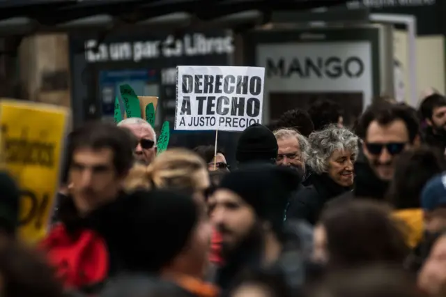 Manifestantes con un cartel que lee "Derecho a techo a justo precio" en España