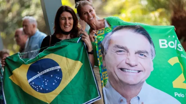 Duas mulheres sorrindo e mostrando para a câmera bandeira do Brasil e imagemjogos de apostas on line gratuitosBolsonaro