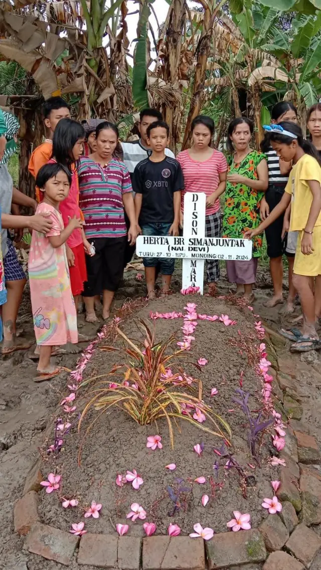 Keluarga berfoto di makam Hertalina Simanjuntak