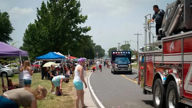 Personas al borde de una calle viendo el desfile del 4 de julio