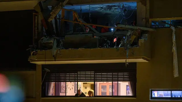 晚上，救援人員在襲擊現場的廢墟中工作，他們戴著頭燈。