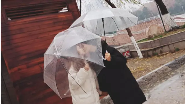 Yang Xi kisses her same-sex partner Liu Ting under their umbrellas