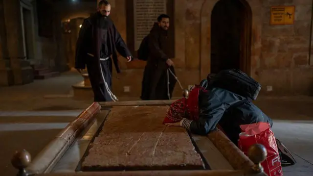 Kobieta modli się przy Płycie Namaszczenia w Bazylice Grobu Pańskiego na Starym Mieście w Jerozolimie, 16 grudnia 2025 roku.
