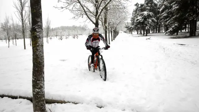 ชายคนหนึ่งพยายามขี่จักรยานเสือภูเขาให้เคลื่อนไปได้ท่ามกลางหิมะที่ปกคลุมพื้นดินที่สวนสาธารณะแห่งหนึ่งในเมืองวิคตอเรีย ทางเหนือของสเปน