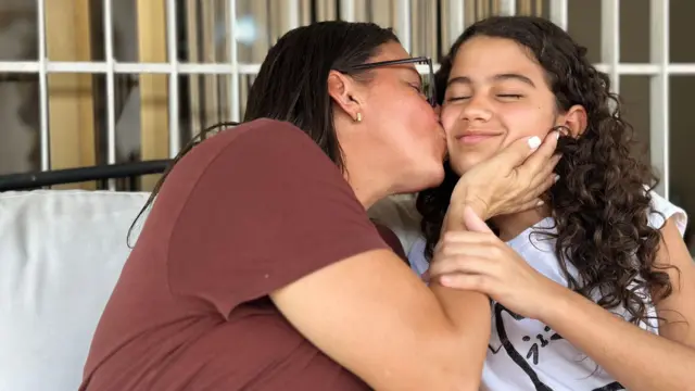 Karina (à esquerda) beija sua filha Fabiana.