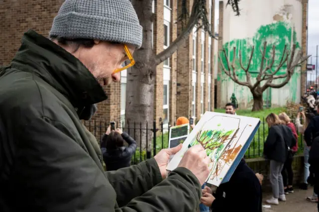 Homem desenhando à distância da obrasportingbet cnpjBanksy