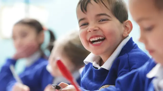 Niño en edad escolar riendo en su aula de clases.
