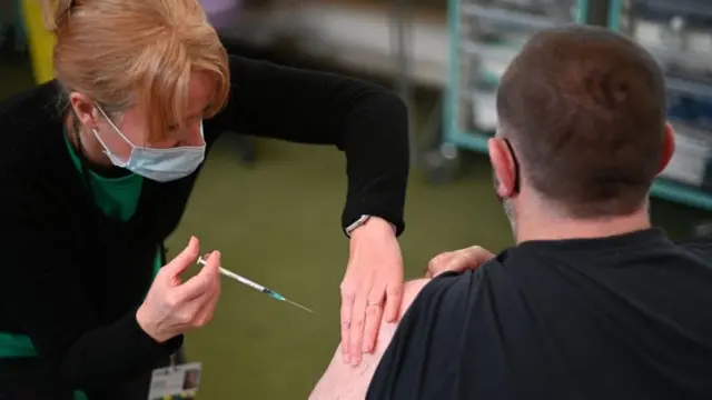 कोभिड-१९ को खोप लगाउँदै एक मानिस।