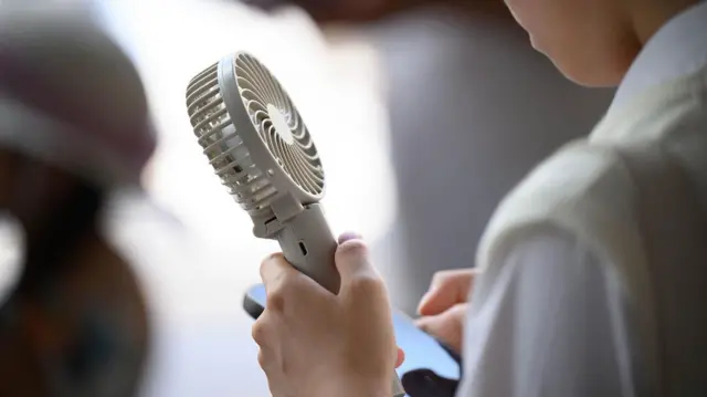 一個人手持一把小風扇