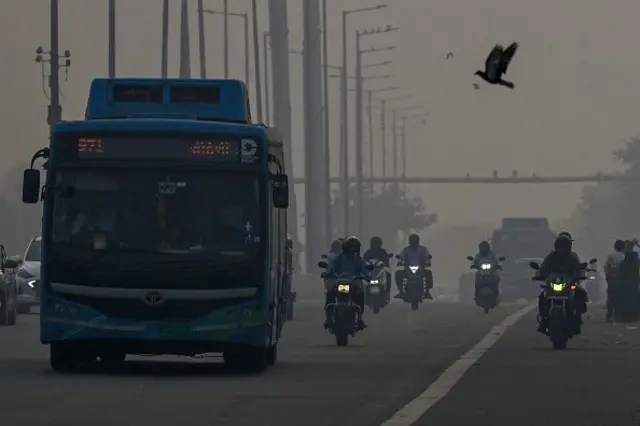 Para komuter berkendara di tengah kabut asap tebal di New Delhi pada 21 Oktober 2025, saat kabut menyelimuti cakrawala kota sehari setelah perayaan Diwali, festival lampu Hindu.