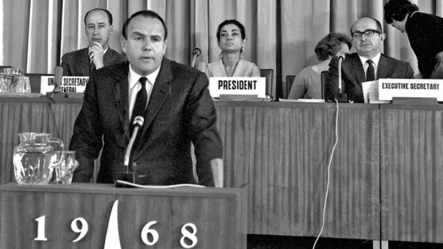 پرنس صدرالدین آقاخان، کمیسر عالی پناهندگان سازمان ملل متحد، در حال ایراد سخنرانی در نشست عمومی کنفرانس بینالمللی حقوق بشر. اشرف پهلوی، رئیس کنفرانس در جایگاه در عکس دیده میشود