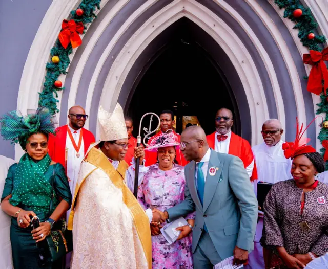 Governor Babajide Sanwo-Olu shakes hand with a clergyman as people gather