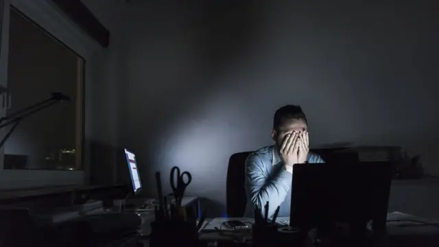 Homme d'affaires épuisé, assis à son bureau le soir.