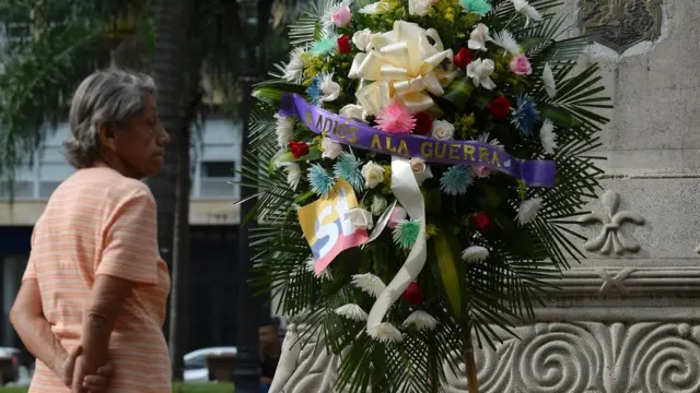 Una corona de flores con el mensaje adiós a la guerra.