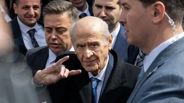 Devlet Bahçeli ülkücü işareti yaparak yürüyor.
