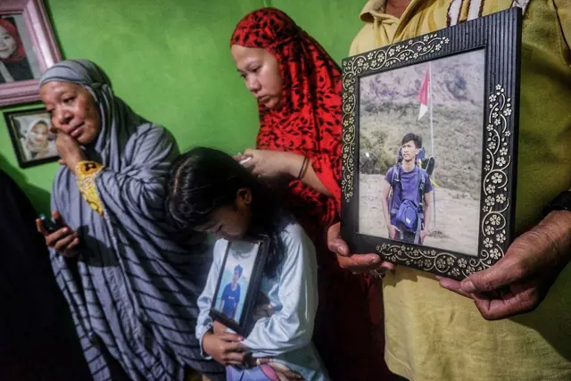 Keluarga memegang potret mendiang Rusdam Diansyah, pengemudi ojek daring yang dikabarkan tewas setelah dikira sebagai anggota intelijen polisi saat unjuk rasa di Makassar, Sulawesi Selatan, pada 1 September 2025.