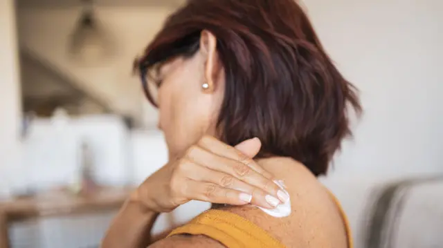 Uma mulher aplicando creme hormonal na pele