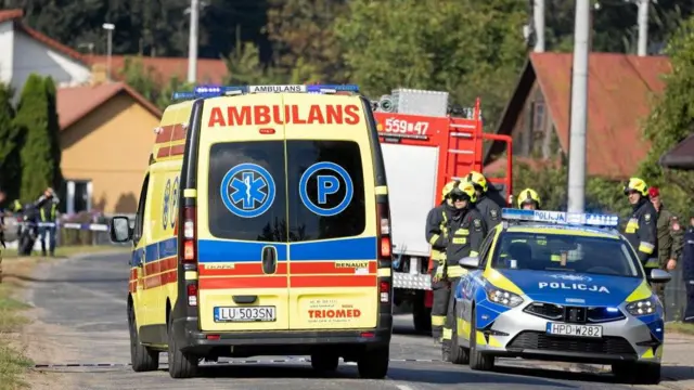 Una ambulancia pasa junto a un agente de policía y bomberos después de que un dron o un objeto similar impactara un edificio residencial.