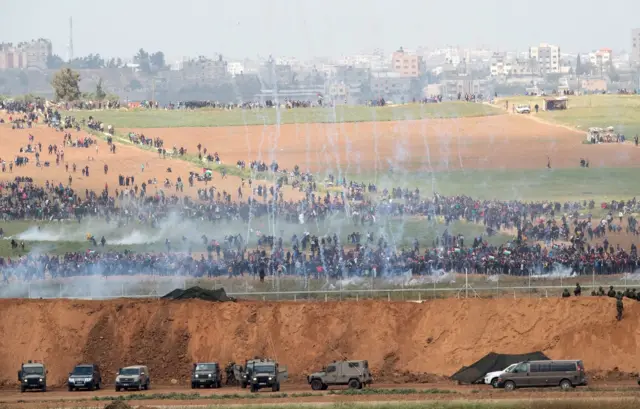 Israeli troops fire tear gas towards Palestinian protesters marching towards the Israeli Gaza border near Nir Am and next to the Gaza town of Beit Hanun, 30 March 2018.