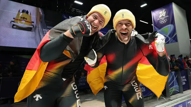 Пилот Йоханнес Лохнер и Георг Фляйшауэр из команды Германии празднуют завоевание золотых медалей после выступления в четвертом заезде двойки бобслея на 11‑й день Зимних Олимпийских игр «Милано–Кортина 2026» на трассе в Кортина‑д’Ампеццо, Италия, 17 февраля 2026 года.