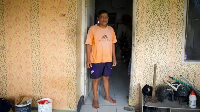 Arbas Batubara berdiri di depan rumahnya. Ia sudah tinggal di sana sejak 2019. 