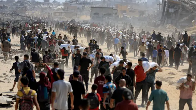 فلسطينيون يحملون مساعدات في بيت لاهيا شمال قطاع غزة في 20 يوليو/تموز 2025