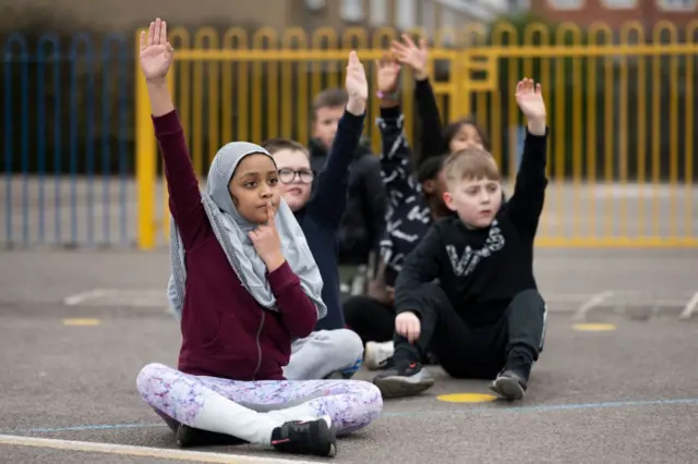 मैदान में बैठे बच्चे