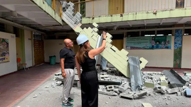 Claudia Arenas y un hombre están en el patio de un colegio del que se desprendió parte del techo