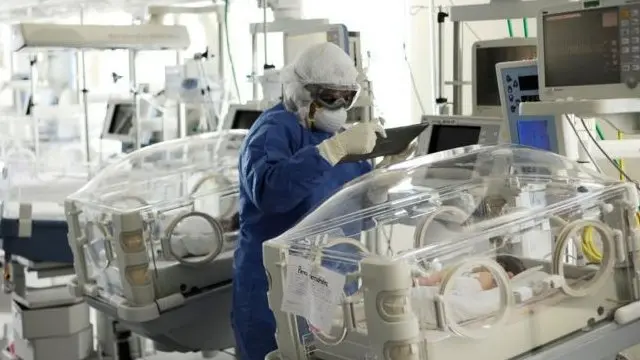 ممرضة ترتدي معدات الوقاية الشخصية أثناء فحص طفل موضوع في مستشفى بالمكسيك