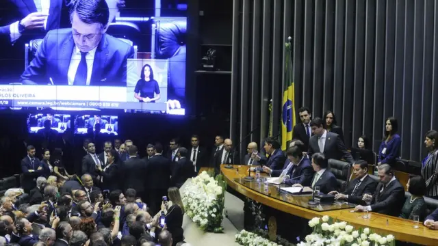 Bolsonaro no Congressoseu primeiro diamandato,que aparece na mesa e no telão assinando documento