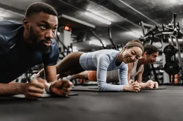 মাটিতে ঝুঁকে ব্যায়াম করছেন দুইজন পুরুষ ও একজন নারী