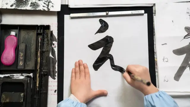 Seorang anak berlatih menulis aksara Jepang.