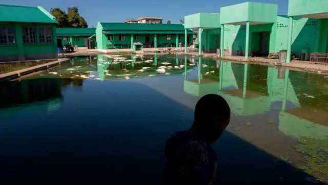 A child looks at the 12 de Octubre elementary school's waterlogged playground in Beira, Mozambique, on January 27, 2021, after Cyclone Eloise made landfall in Beira on January 23, 2021.