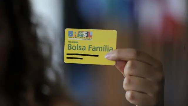 Beneficiária segura cartão do Bolsa Família