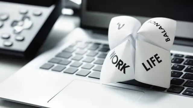 Papel en el que se lee "vida" y "trabajo" sobre una computadora.