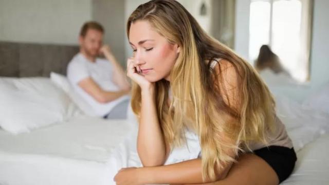 Mulher pensativa diantemega sena quinta feirahomem chateado ao fundo