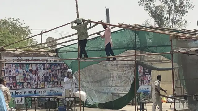 ਗਰਮੀ ਤੋਂ ਬਚਣ ਲਈ ਬਾਂਸ ਅਤੇ ਘਾਹ ਦੀ ਛੱਤ ਦੇ ਉੱਪਰ ਤਰਪਾਲ ਪਾਈ ਜਾ ਰਹੀ ਹੈ ਤਾਂ ਜੋ ਮੀਂਹ ਦਾ ਪਾਣੀ ਅੰਦਰ ਨਾ ਆਵੇ