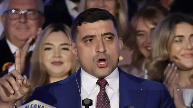 右手の人差し指を立てて演説する男性