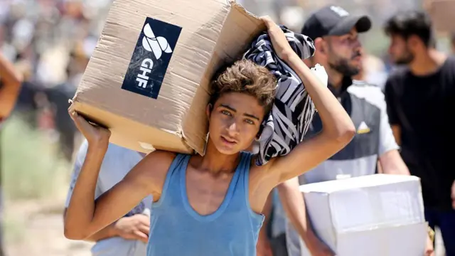 Un joven carga con una caja de ayuda humanitaria.