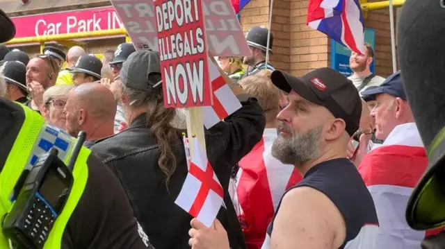 Протестующие в Бристоле белые мужчины среднего возраста с английскими флагами и плакатом «Выслать нелегалов немедленно»