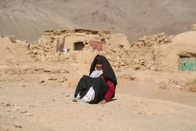 زنی پس از زلزله‌ای که در افغانستان اتفاق افتاد، در برابر آوارها نشسته‌است 