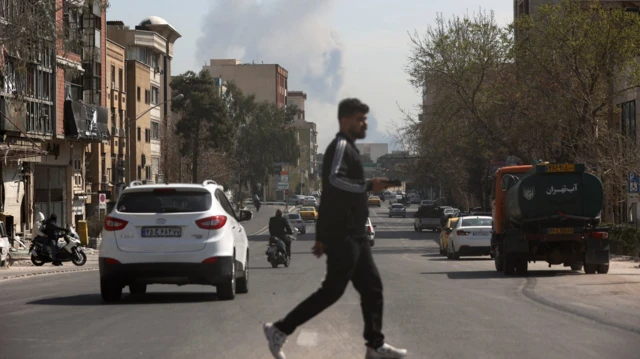 Мушкарац у тамној одећи прелази улицу у Техерану