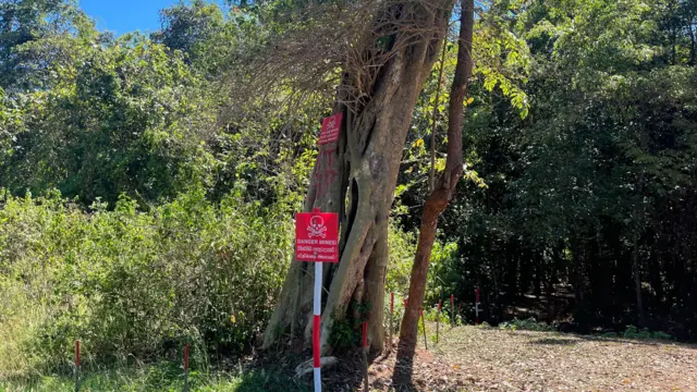 තවමත් බිම්බෝම්බ ඉවත් කර නොමැති මුලතිව්හි ප්‍රදේශයක්. රතු පැහැයෙන් බිම්බෝම්බ අනතුරුදායකයි යනුවෙන් සඳහන් කළ පුවරුවක් දැක්වේ 