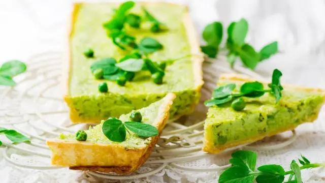 Тарталетка с горохом и разбросанными сверху зелеными гороховыми листьями